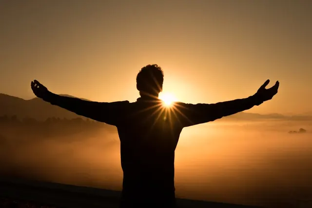 Silhouette einer Person bei Sonnenuntergang am Wasser
